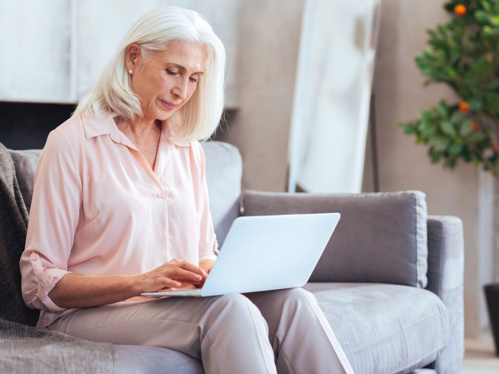 Woman sitting on couch using laptop computer