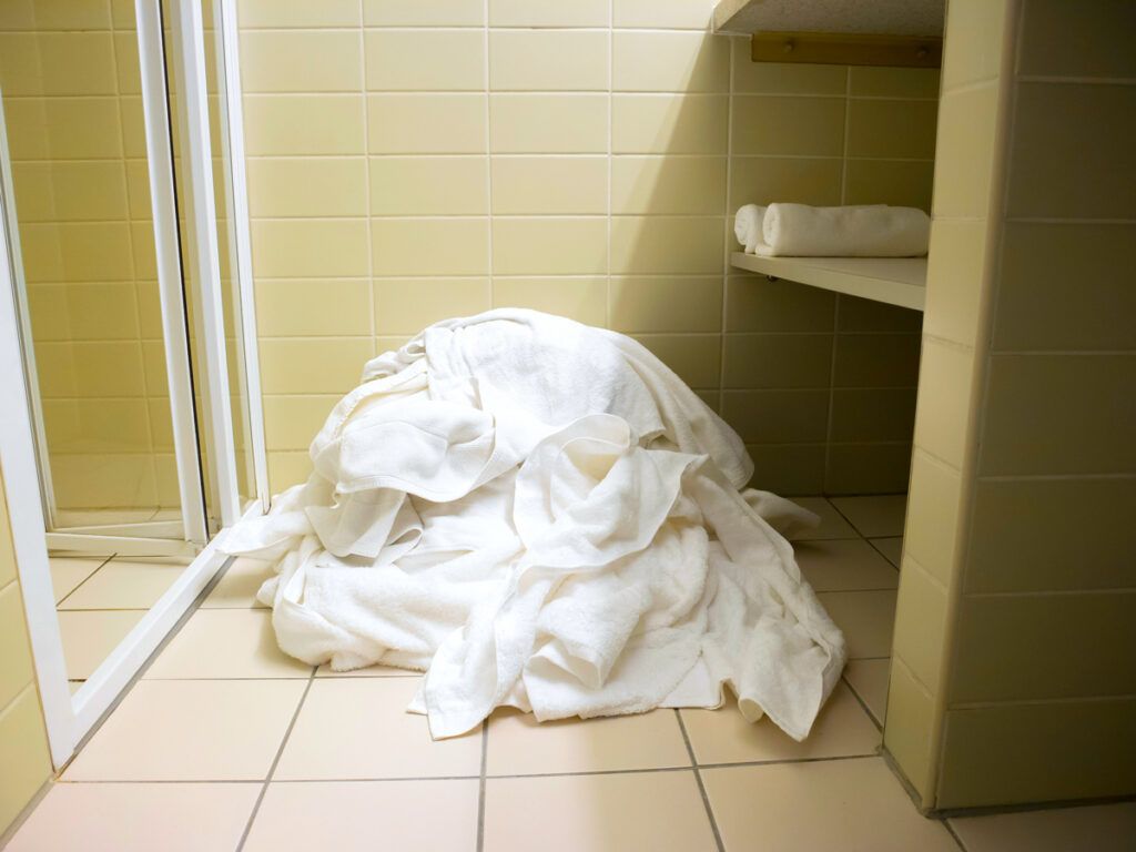 Pile of used linens on hotel bathroom floor
