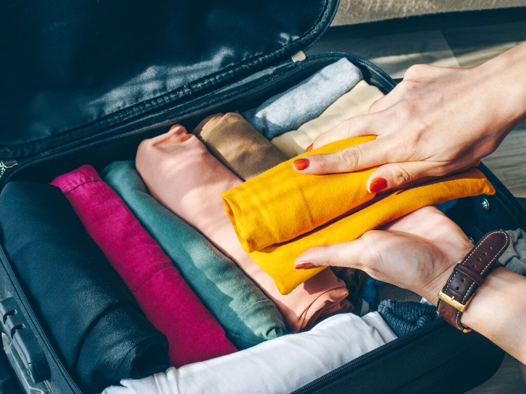 Traveler rolling shirts to pack in suitcase