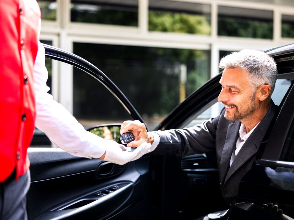 Man handing car keys to valet attendant