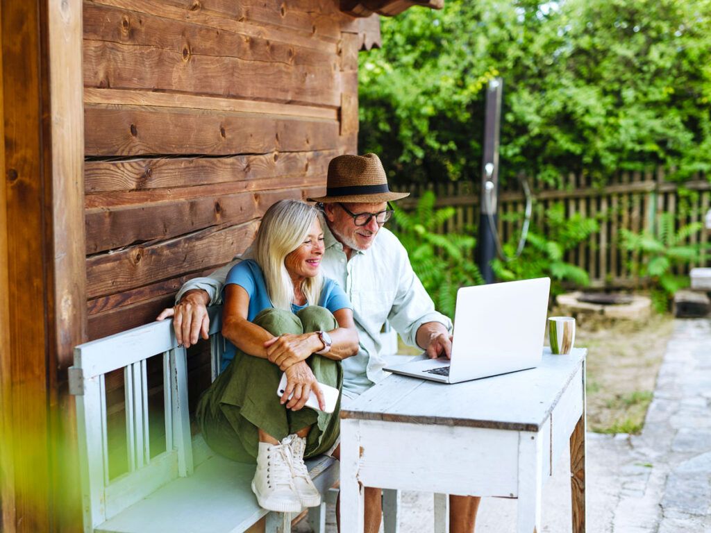 Couple sitting at a table outside looking at laptop