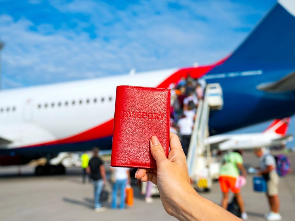 Traveler holding up passport in front of plane