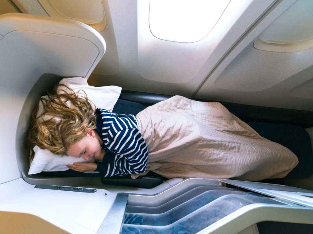 Traveler sleeping in lie-flat business-class seat