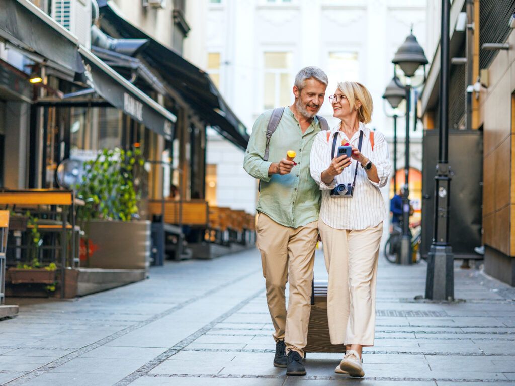 Couple walking through city with luggage and ice cream