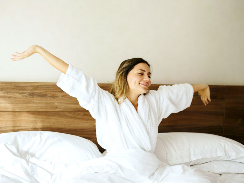 Hotel guest stretching in bed