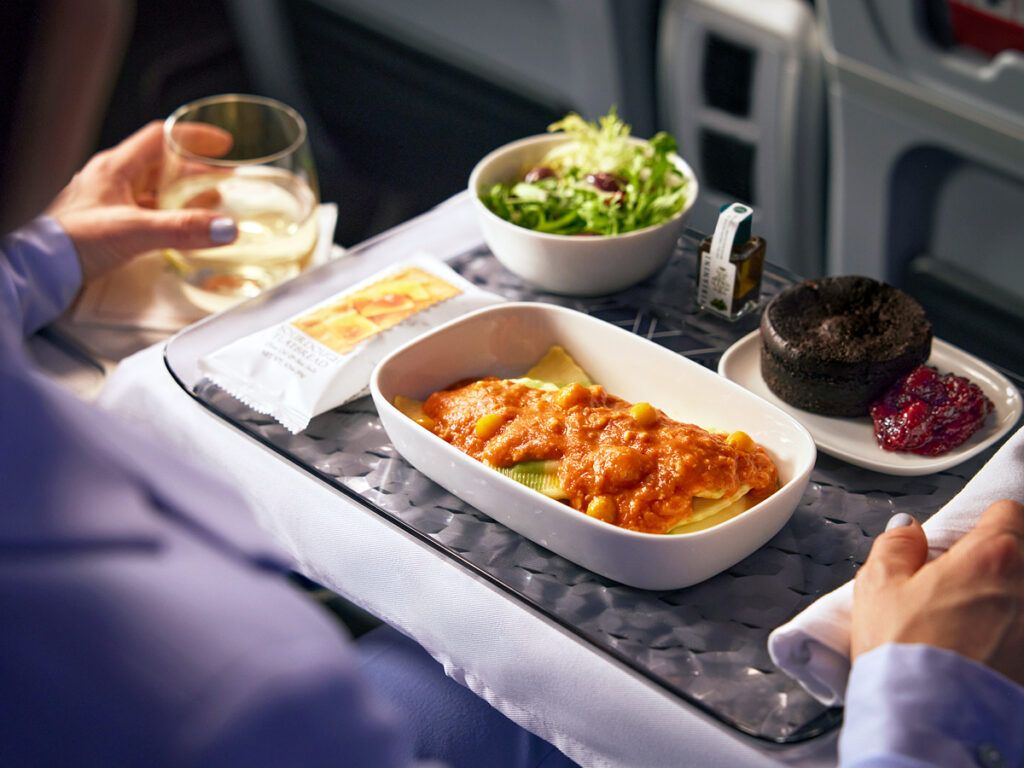 A premium-economy meal of pasta, salad, and dessert