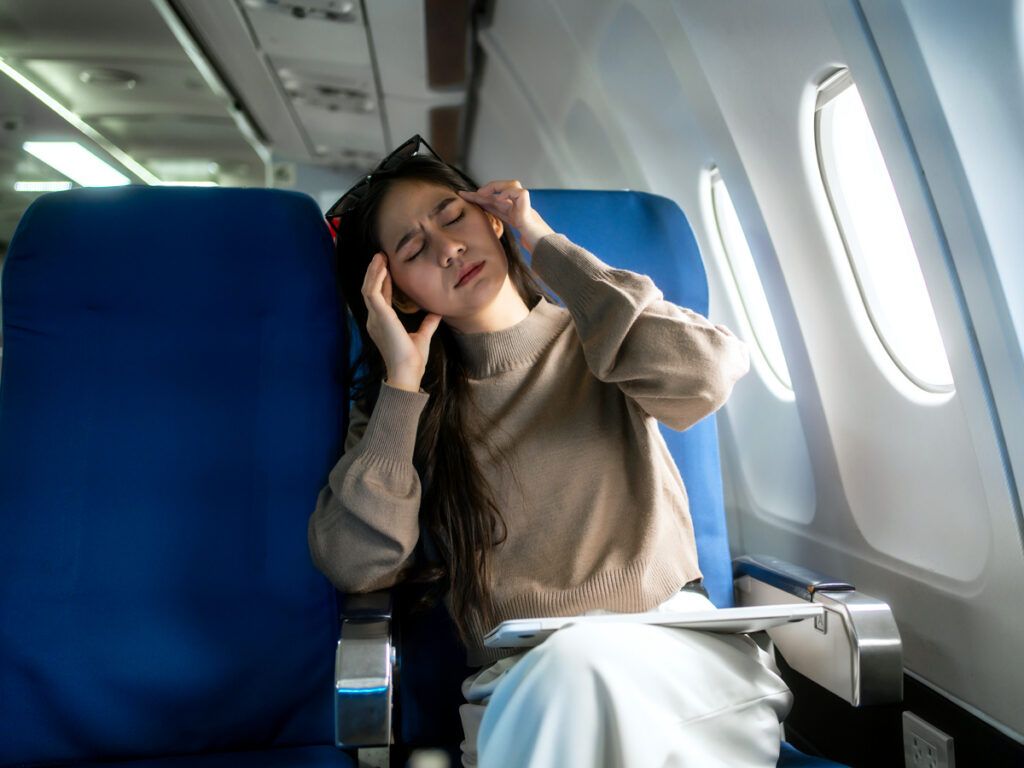 Woman rubbing her head on a plane