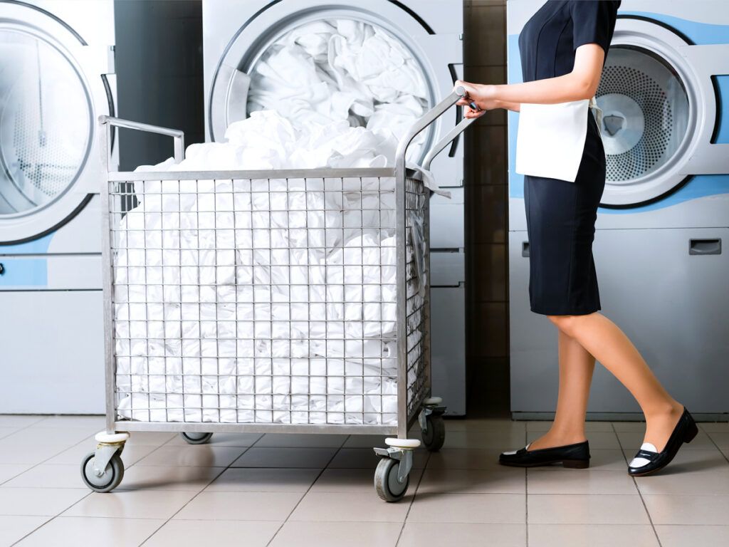 Hotel housekeeper standing near a laundry cart