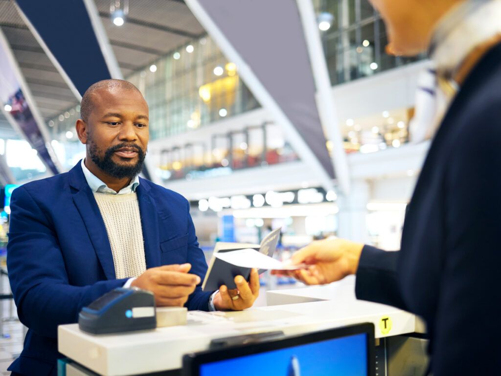 Airline agent handing passenger boarding pass at ticket counter