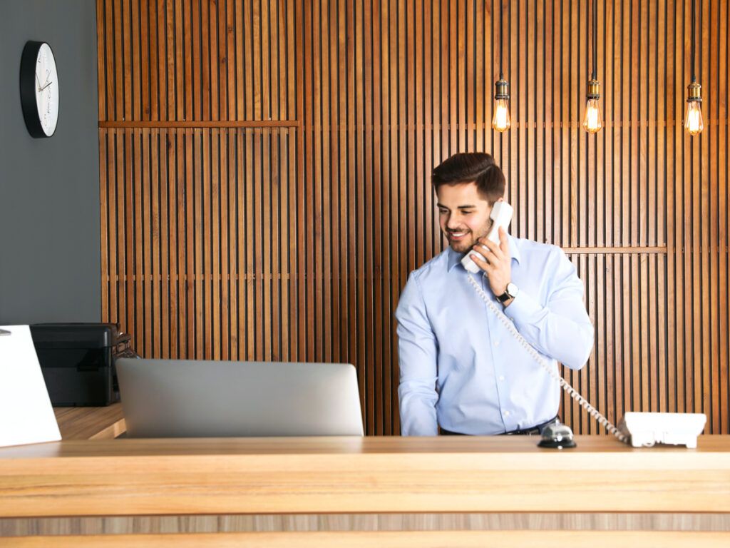 Hotel front desk receptionist speaking on telephone