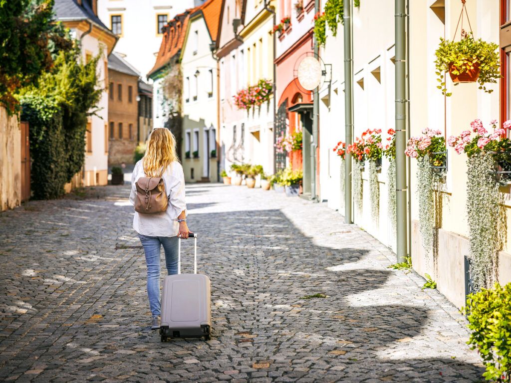 Tourist rolling suitcase on cobblestone street