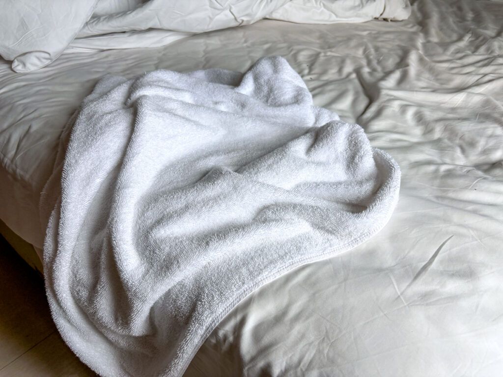 Used white towel on an unmade hotel bed after use