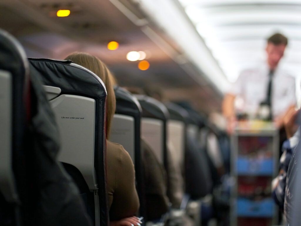 Flight attendant with beverage cart in aisle