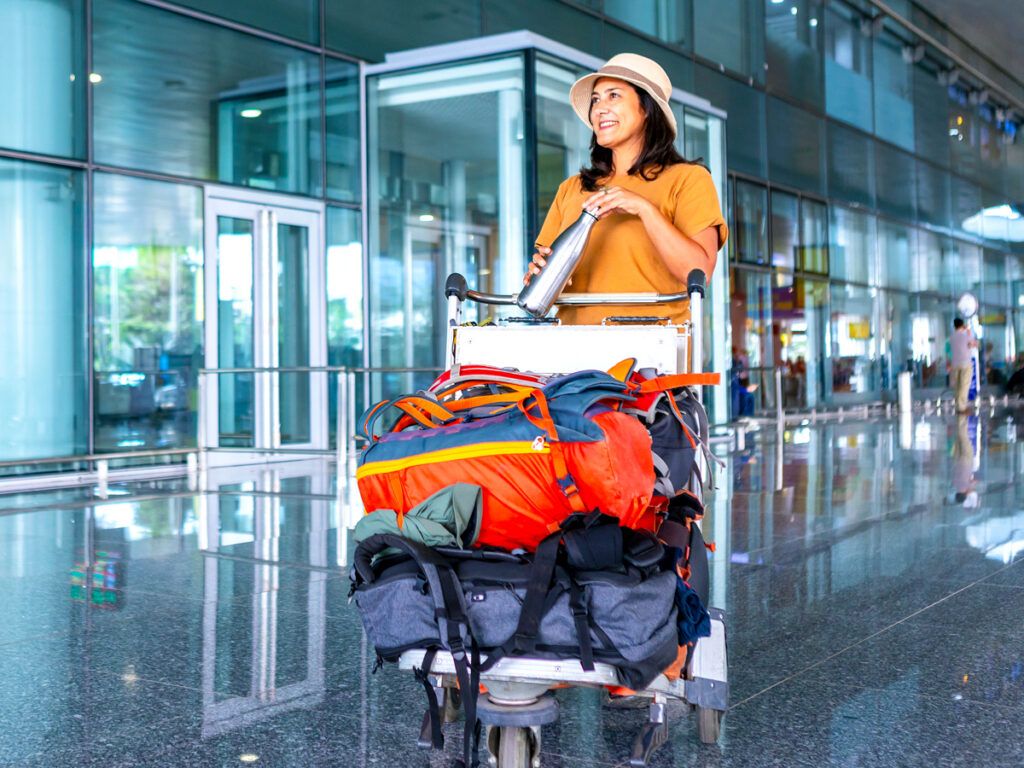 Traveler with water bottle and luggage cart in airport terminal