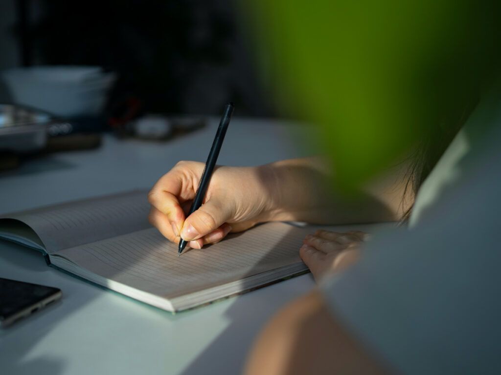 Person writing with pen in notebook