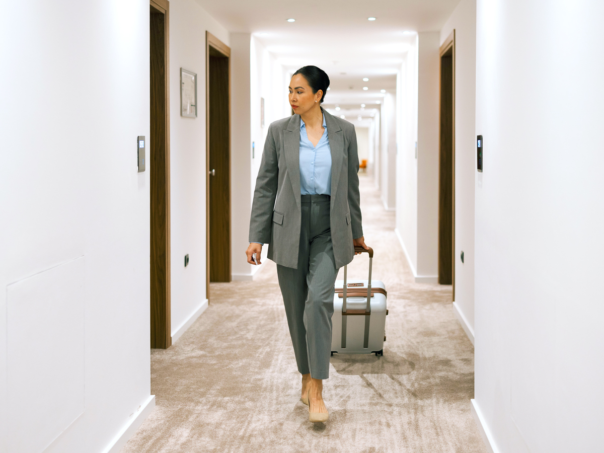 Businesswoman walking through hotel corridor searching for a hotel room