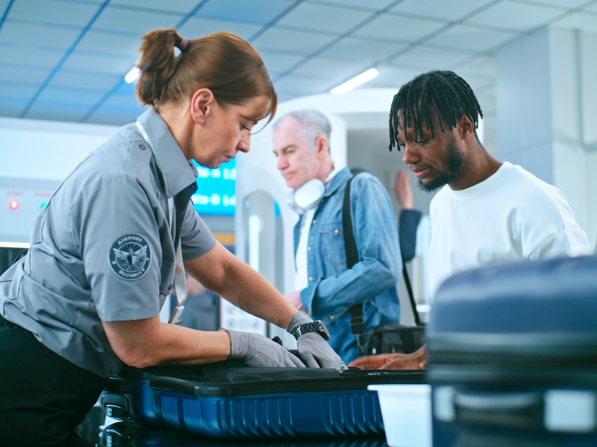 A TSA worker inspecting the baggage of a passenger before boarding