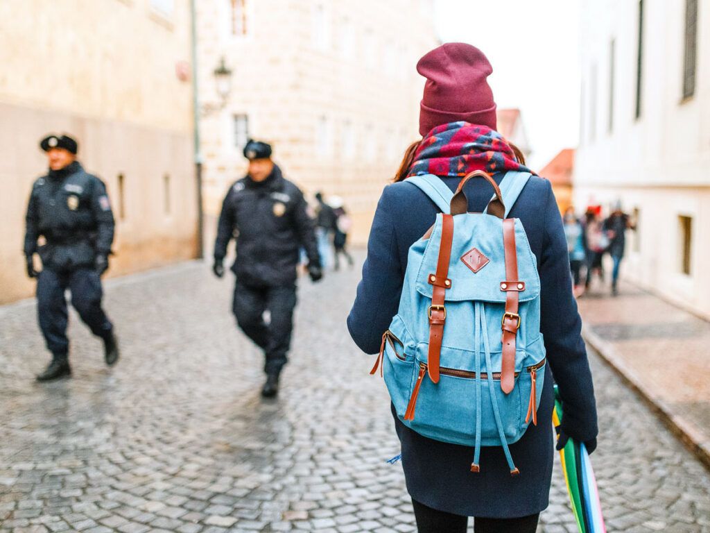 Traveler walking down street past police officers
