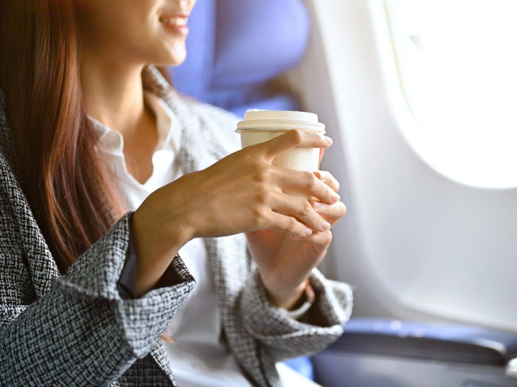 Businesswoman sipping a hot coffee during a flight 