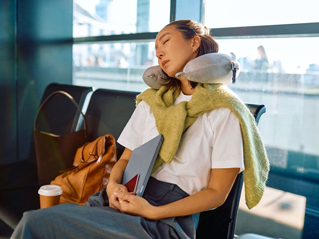 Woman relaxes at the airport using a travel pillow