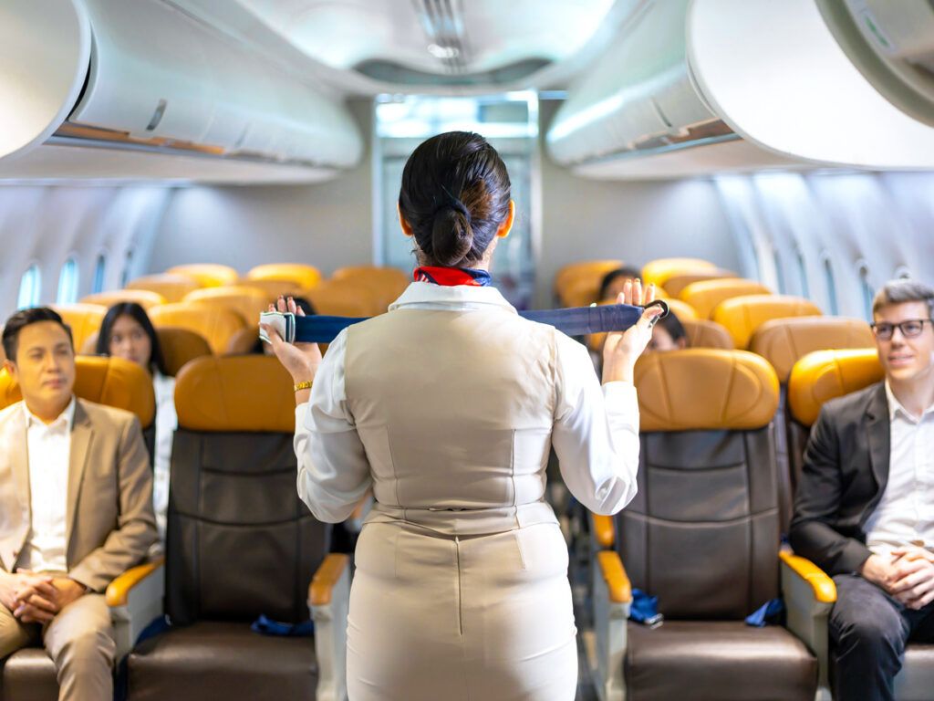 A flight attendant demonstrating safety procedure using a seat belt