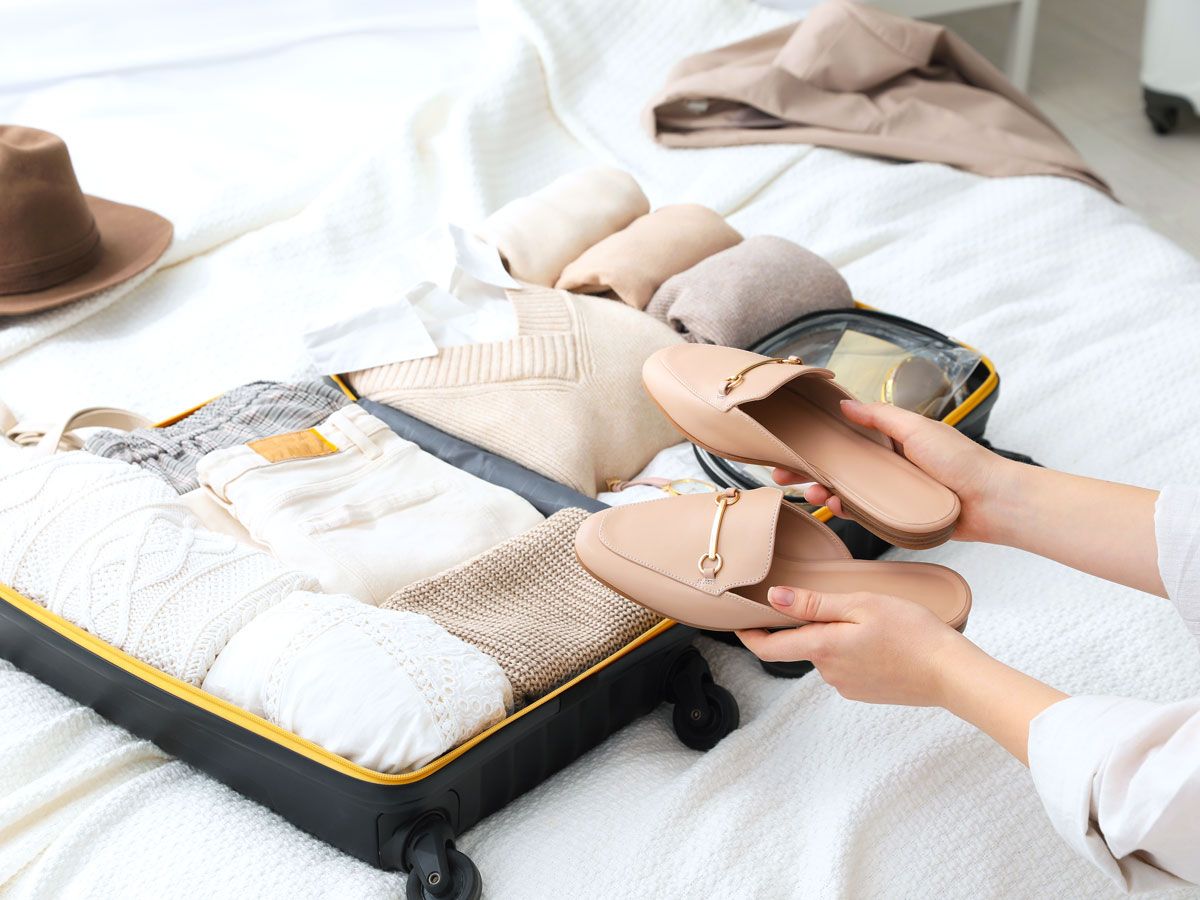Traveler packing shoes in luggage