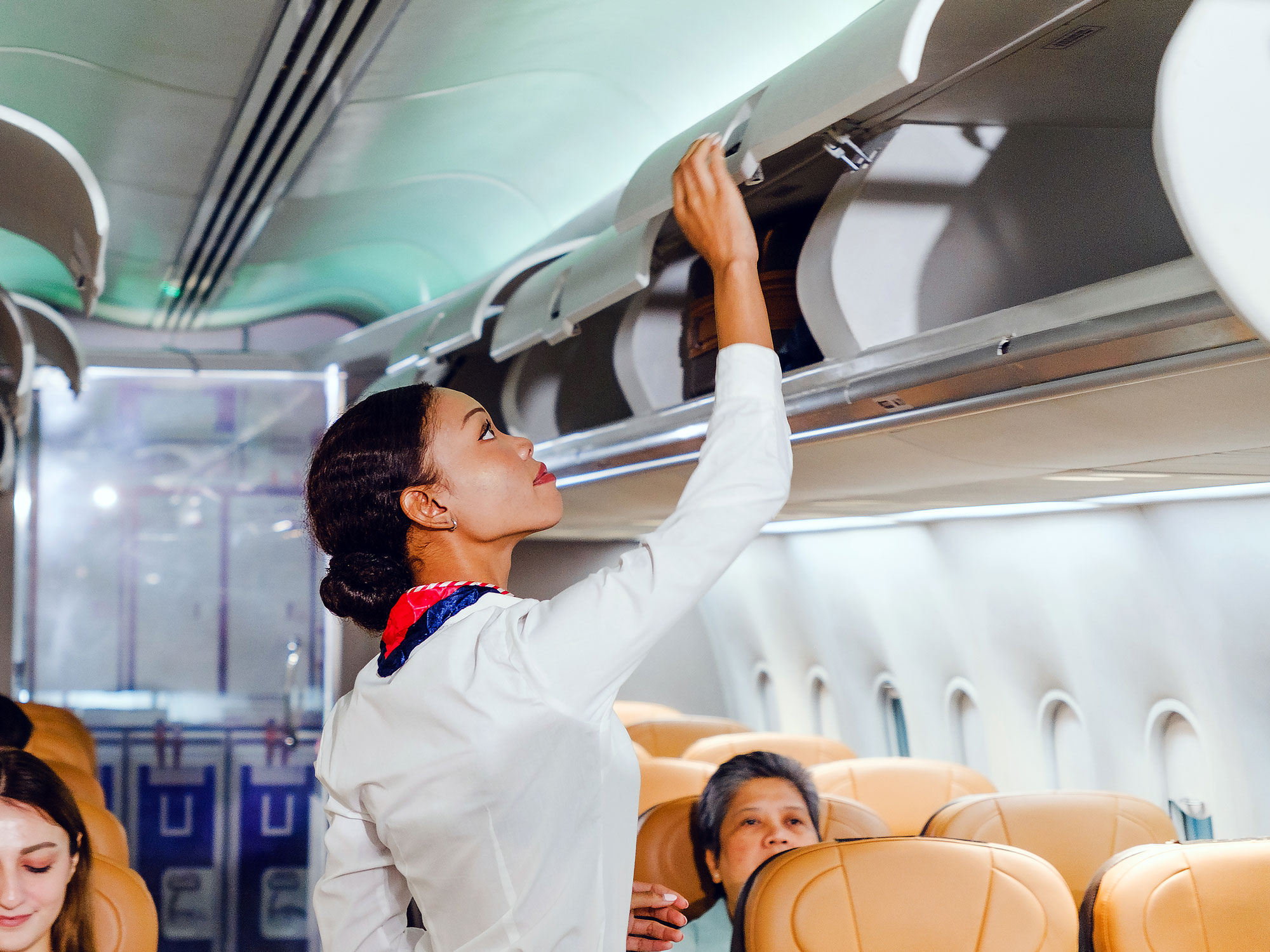 Flight attendant opening an overhead luggage compartment aboard a plane