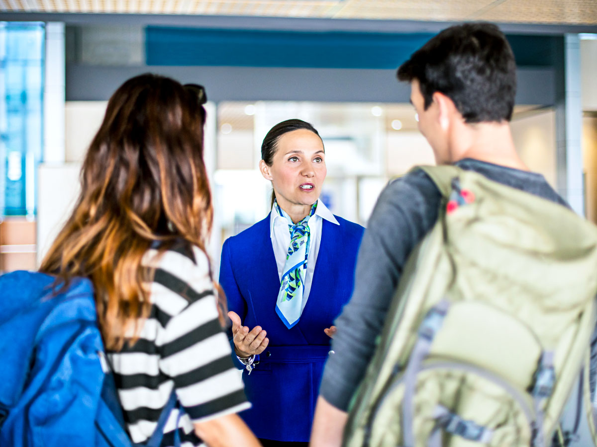 Flight attendant helping a young couple at the airport