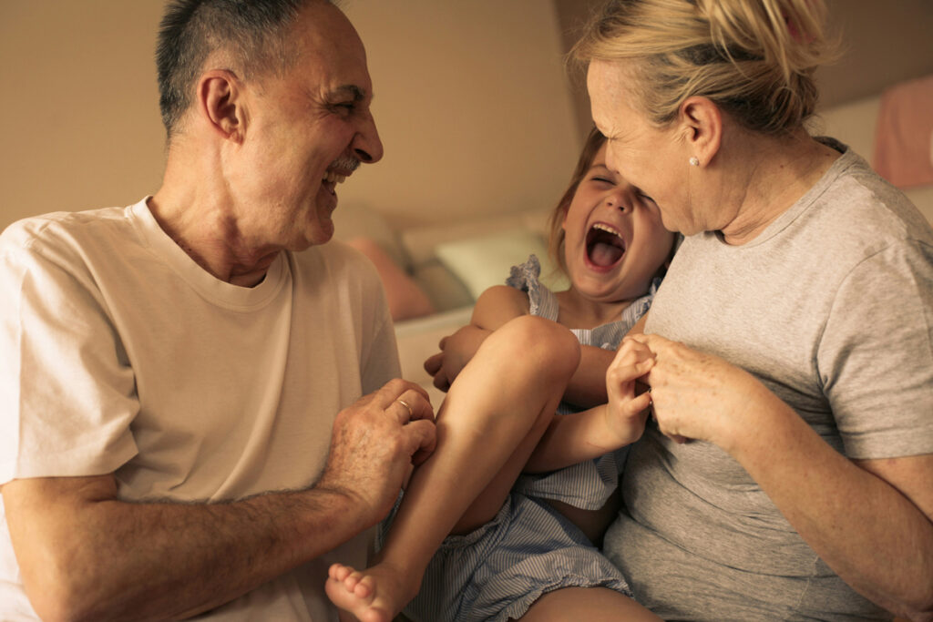 An image of two parents tickling a giggling toddler.