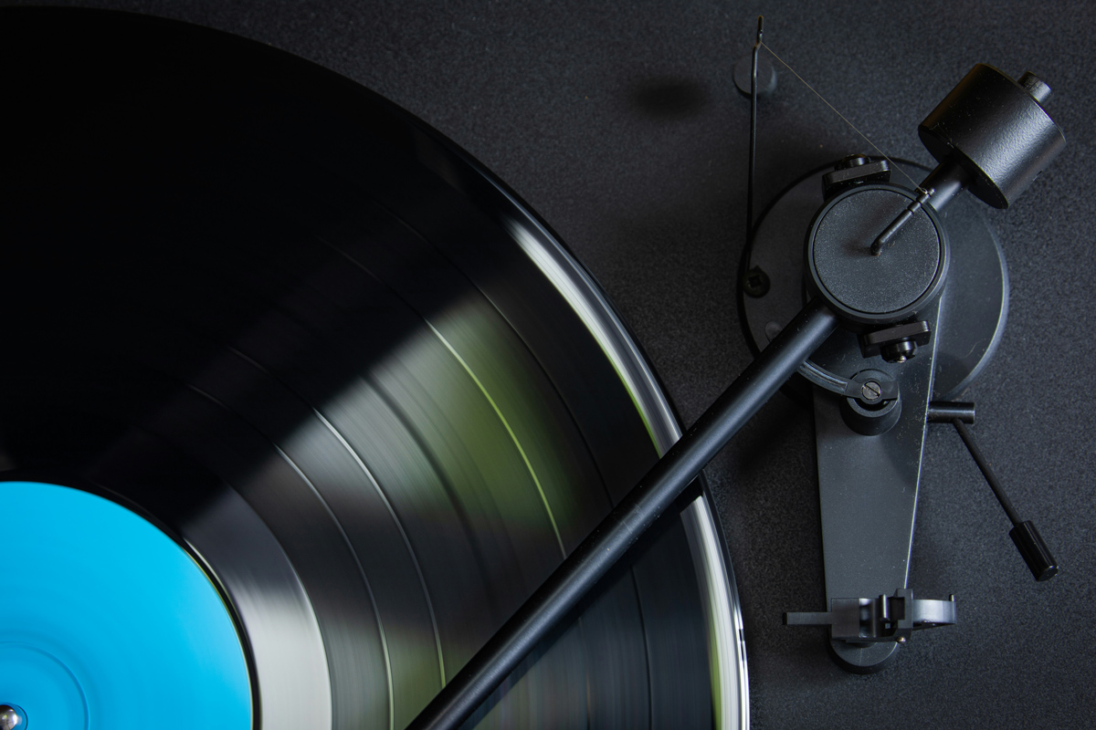 A close-up image of half of a vinyl record with the needle of a record player placed across it