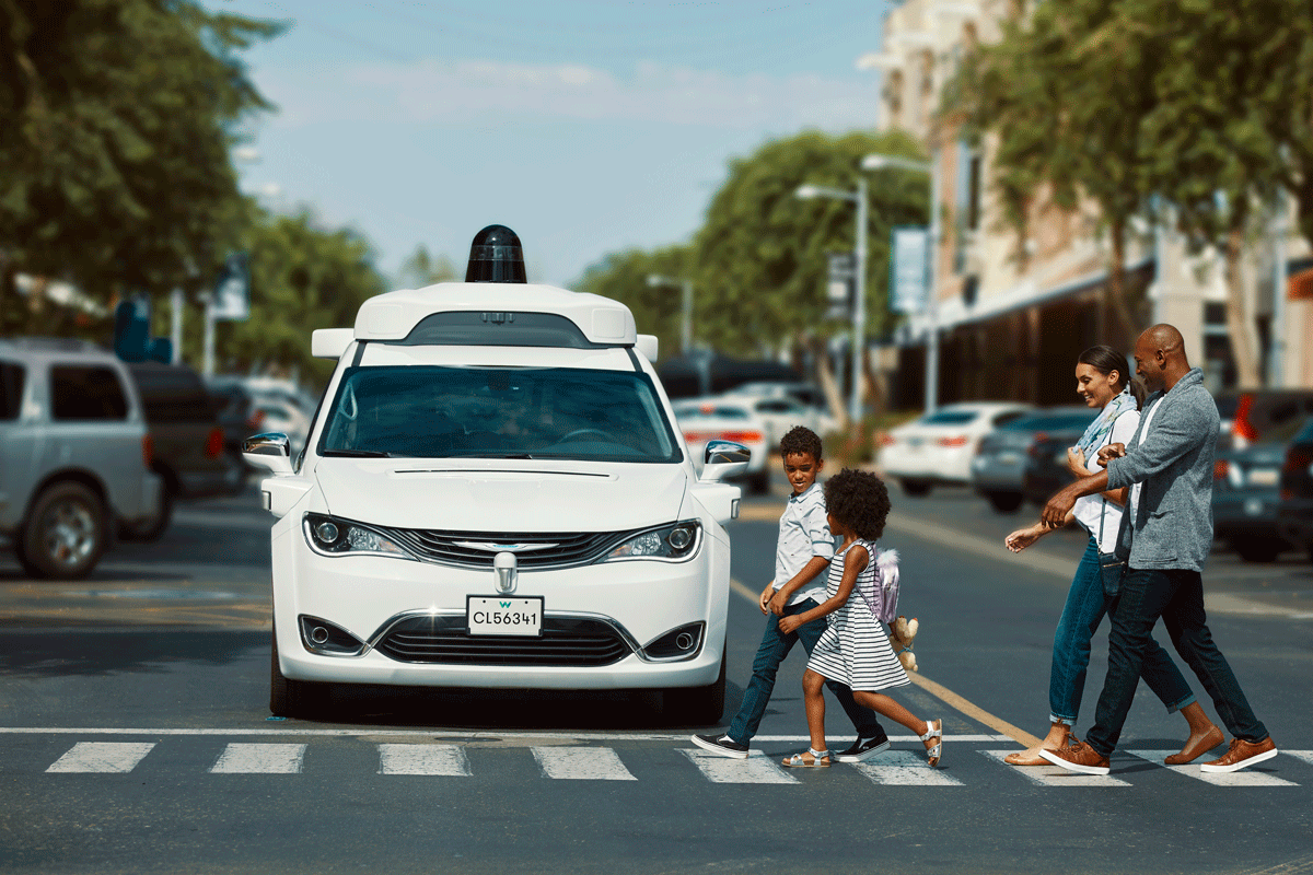 A family crossing in front of a Waymo at a crosswalk