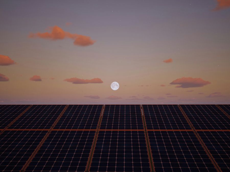 The moon over solar panels at dawn or dusk