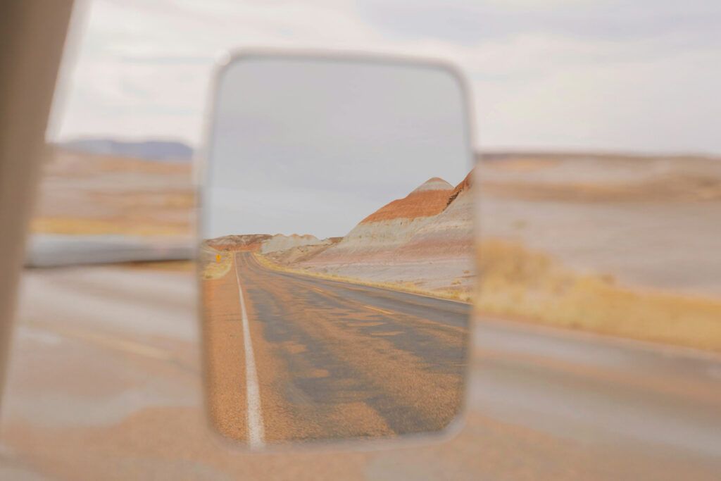 Passenger-side mirror reflecting a desert road