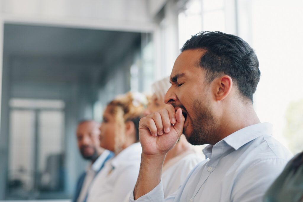 A person yawning during a business meeting
