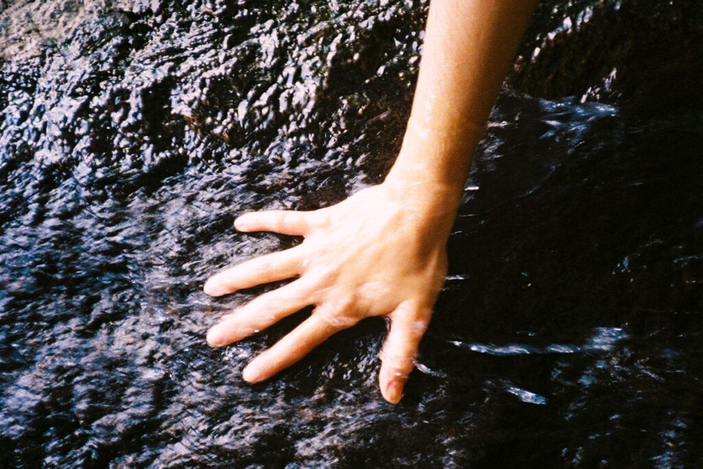 Hand touching a wet rock