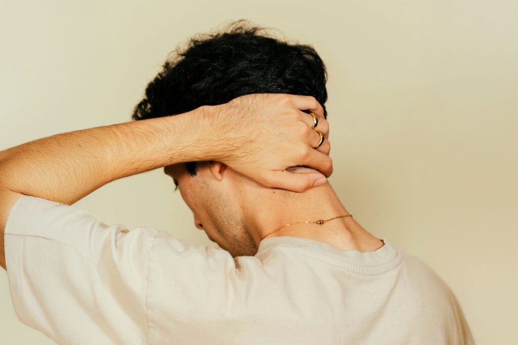 A person feeling the back of their neck