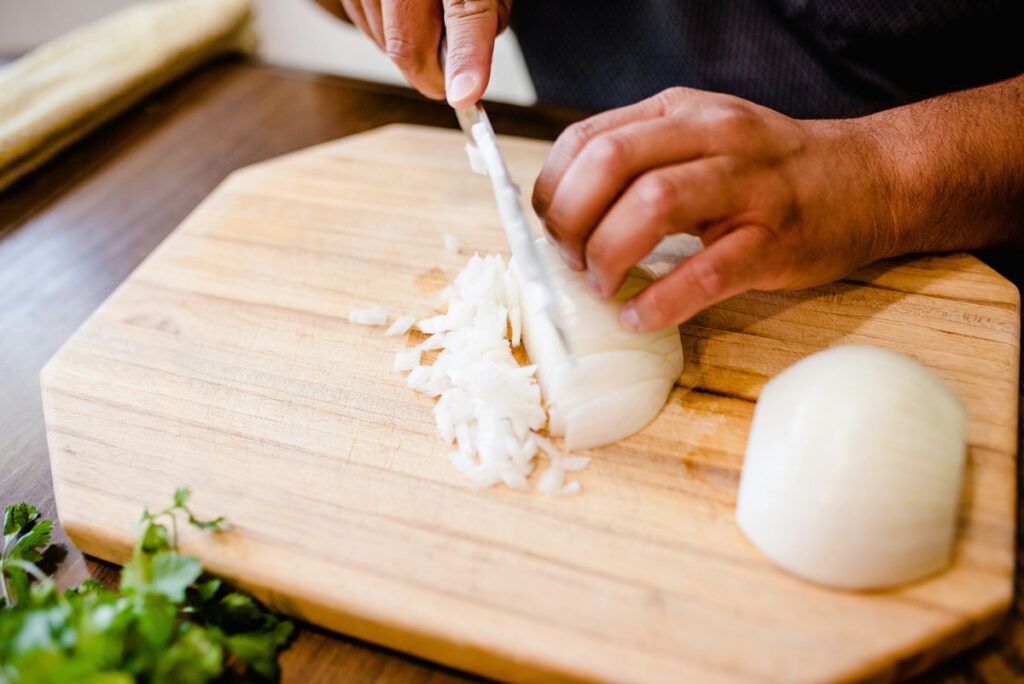 Dicing white onions on cutting board