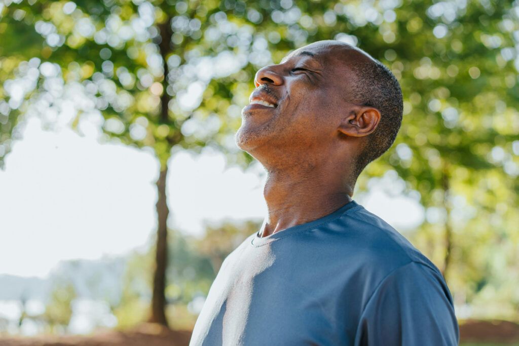 Person taking a big breath of fresh air while outside at a park