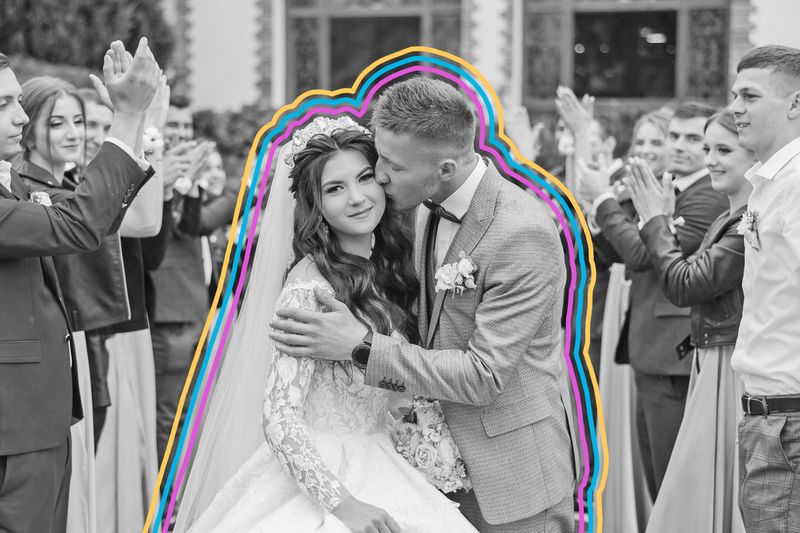 Couple posing together on their wedding day surrounded by wedding guests