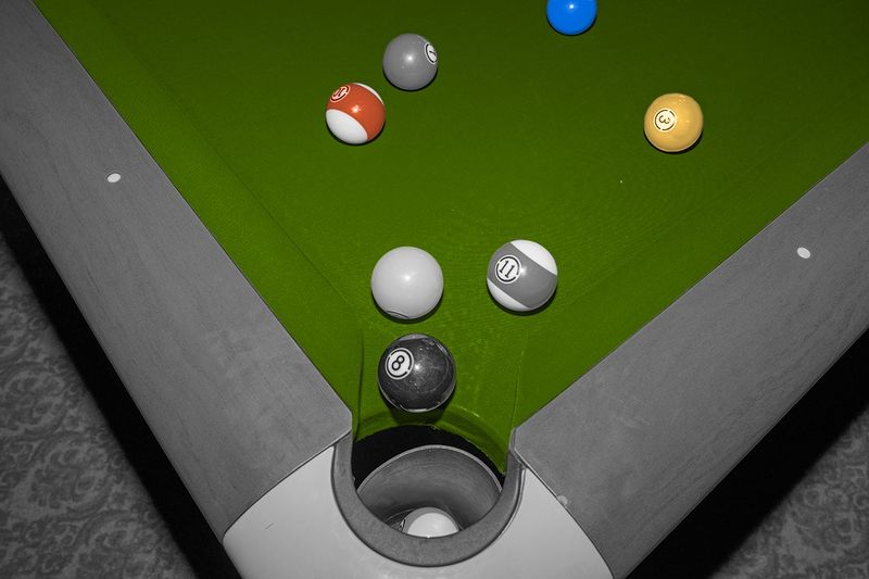 Pool balls clustered in the corner of a pool table