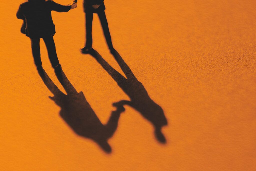 Silhouette of two men shaking hands